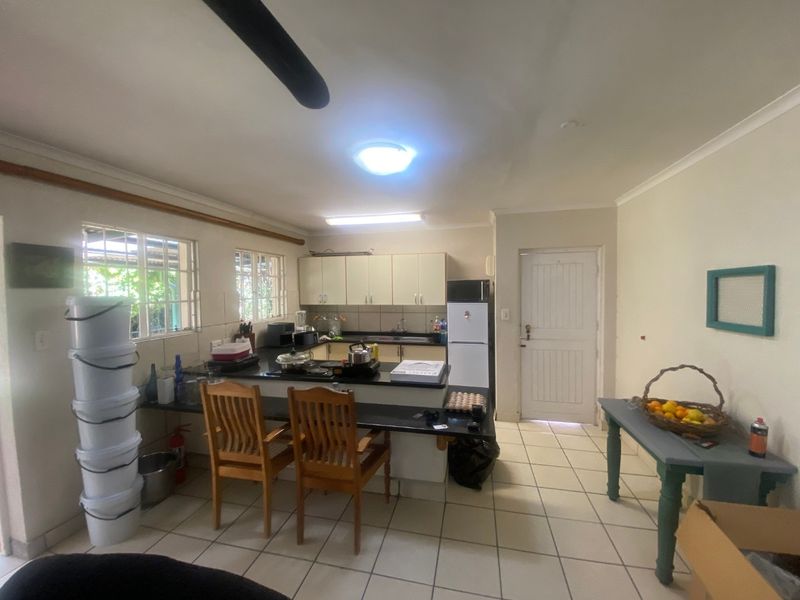A functional kitchen featuring built-in cabinetry, granite countertops, and tiled flooring, with direct access to an exterior door.