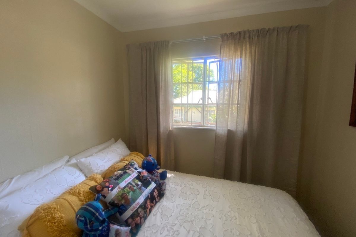A standard bedroom featuring a window with security bars and neutral wall finishes.