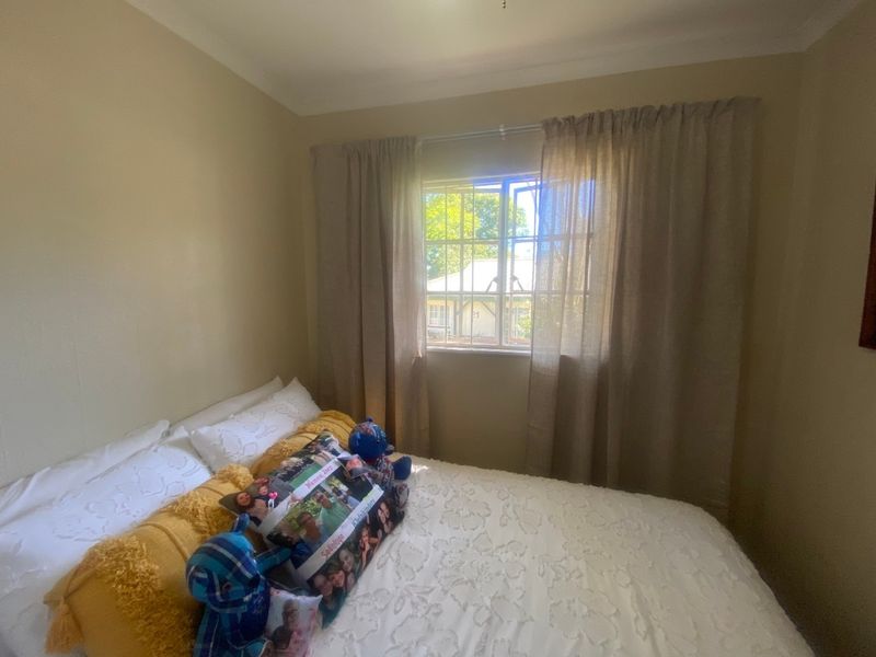 A standard bedroom featuring a window with security bars and neutral wall finishes.