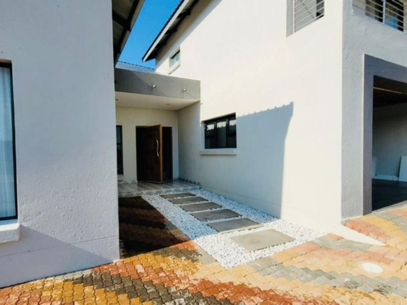 Modern front facade featuring a paved driveway, stone walkway leading to the entrance, and an integrated garage.