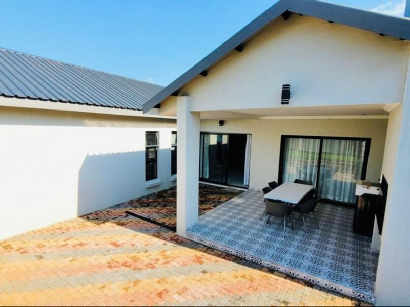 A covered patio area featuring patterned floor tiles, sliding glass doors, and modern exterior lighting, providing a seamless transition to the outdoor space.