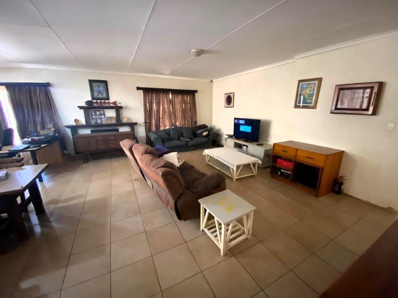 A spacious living room featuring neutral tiled flooring and a coved ceiling, offering a functional layout for comfortable family living.