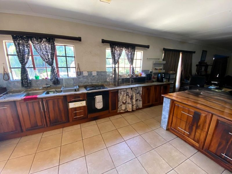 A functional kitchen featuring wooden cabinetry, a built-in oven, hob, and a central island, providing ample workspace and storage in a traditional layout.