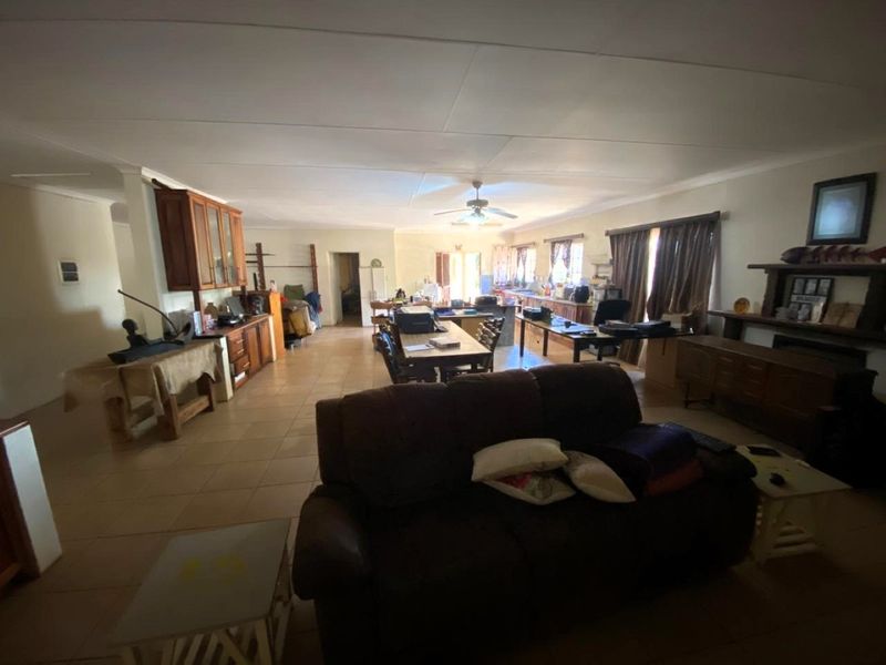 Spacious open-plan living and dining area featuring tiled flooring, ceiling fan, and built-in cabinetry, offering a versatile layout for family living.