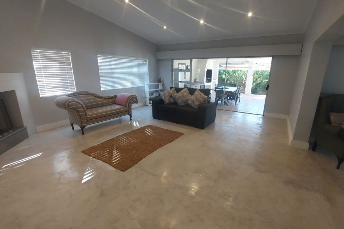 Spacious living room featuring polished concrete floors, a built-in fireplace, recessed lighting, and large sliding glass doors opening to an outdoor patio area.