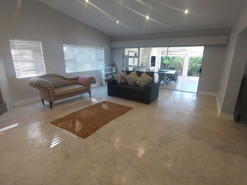 Spacious living room featuring polished concrete floors, a built-in fireplace, recessed lighting, and large sliding glass doors opening to an outdoor patio area.