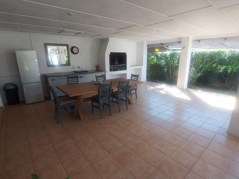 Spacious covered patio featuring a built-in braai, tiled flooring, and built-in cabinetry, providing an ideal space for outdoor entertaining and dining.