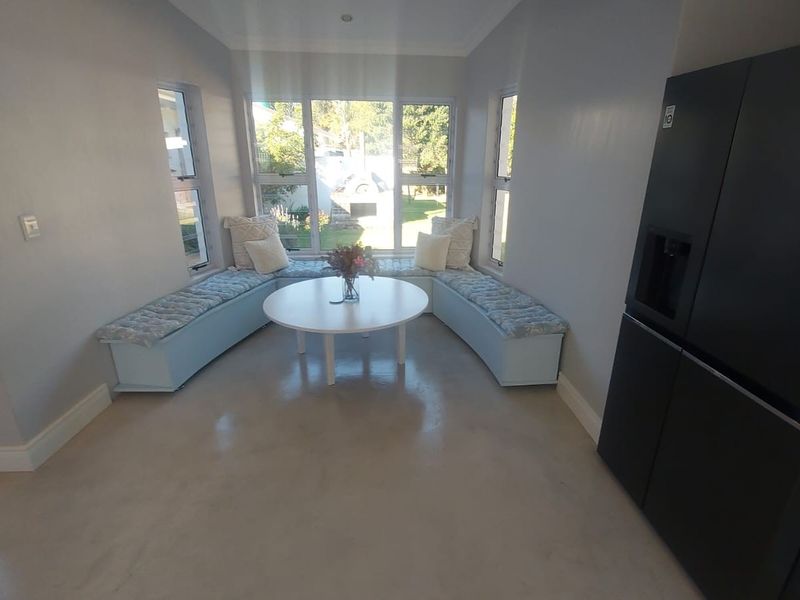 A bright living area featuring polished concrete floors, large windows providing natural light, and custom built-in bench seating.