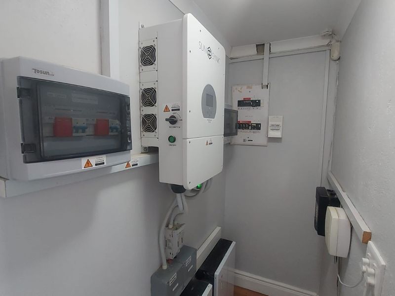 A dedicated utility space featuring a wall-mounted solar inverter system and electrical distribution board infrastructure.