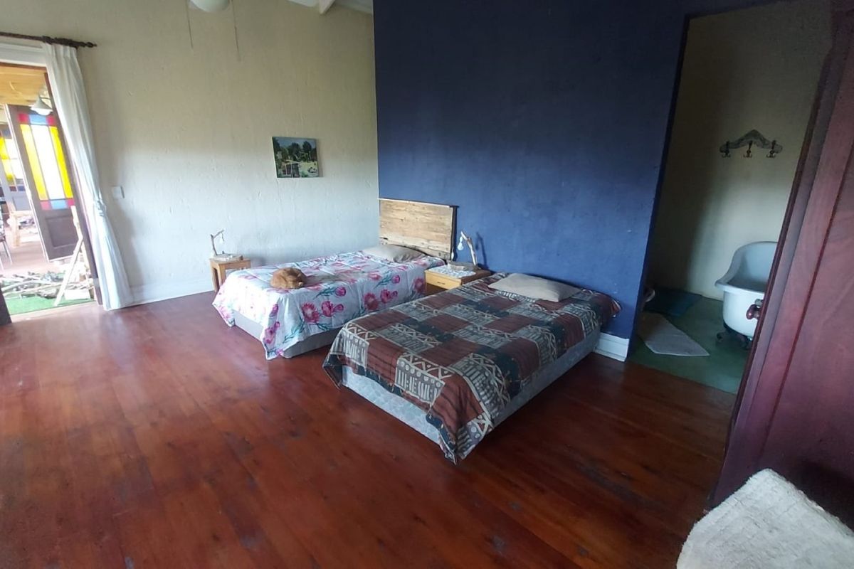 Spacious bedroom featuring original hardwood flooring, a distinctive stained glass door, and direct access to an en-suite bathroom area.