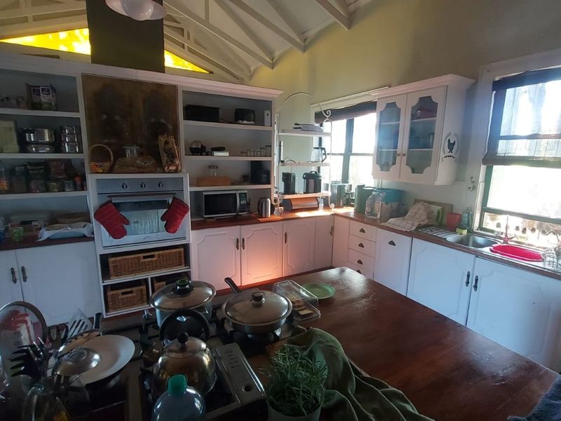 A rustic kitchen featuring white cabinetry, a built-in oven, gas cooktop, and a vaulted ceiling with exposed rafters, offering a warm, traditional aesthetic.
