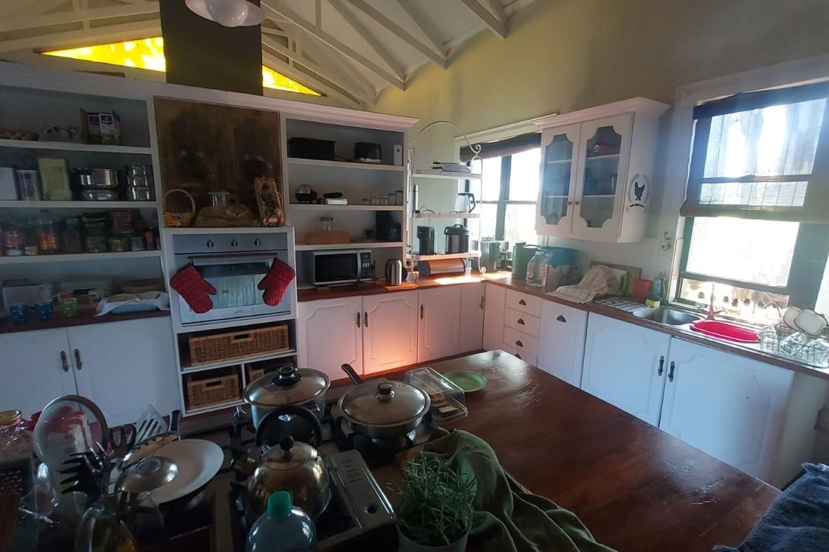 A rustic kitchen featuring white cabinetry, a built-in oven, gas cooktop, and a vaulted ceiling with exposed rafters, offering a warm, traditional aesthetic.