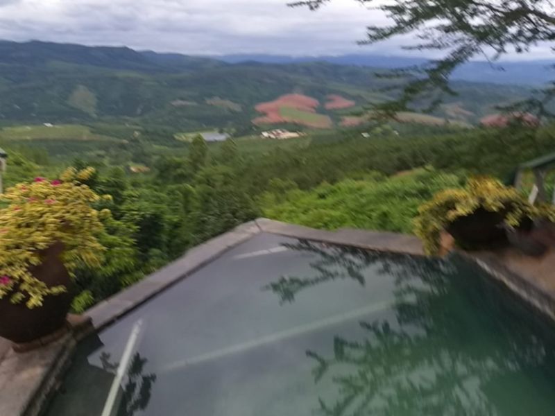 An outdoor swimming pool featuring stone coping, overlooking a scenic valley and mountain landscape.