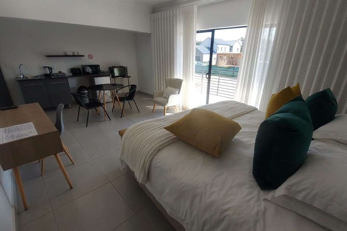 Spacious bedroom featuring a convenient kitchenette area, tiled flooring, and large sliding glass doors providing access to the exterior.