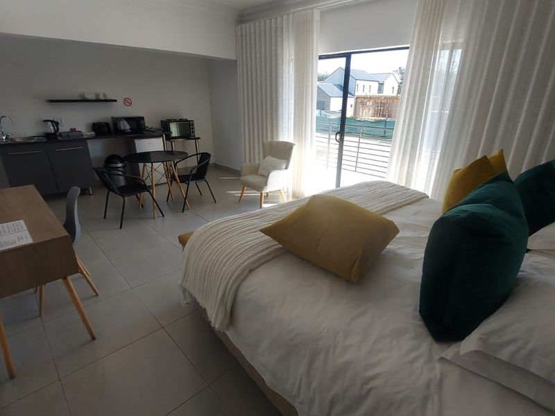 Spacious bedroom featuring a convenient kitchenette area, tiled flooring, and large sliding glass doors providing access to the exterior.