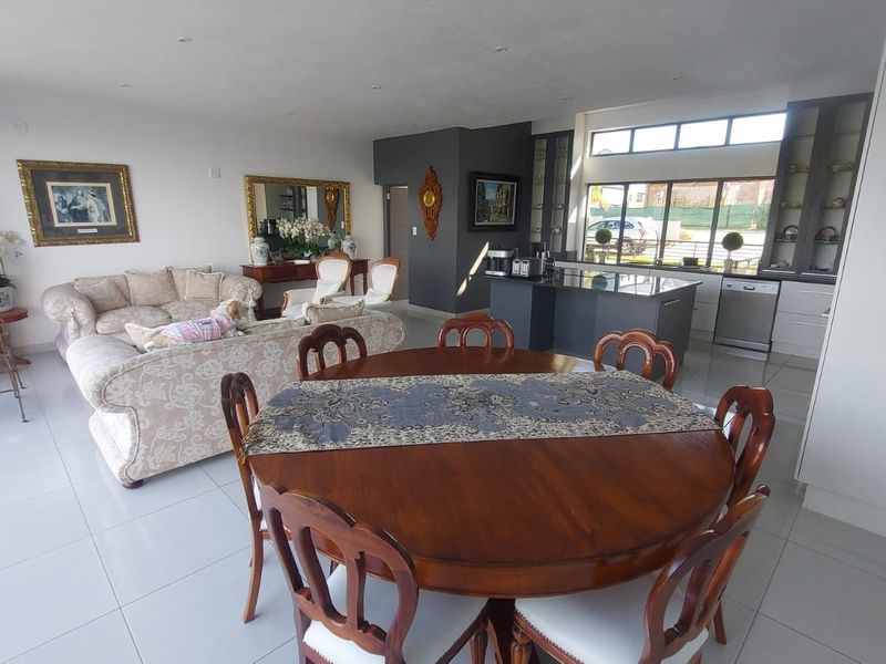 Spacious open-plan living and dining area featuring a modern kitchen with a central island, sleek cabinetry, and large windows providing ample natural light.