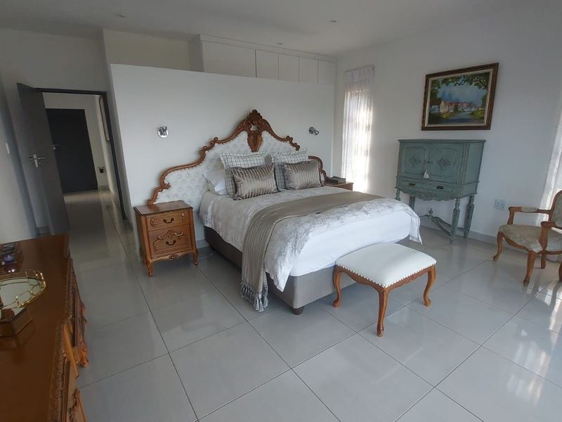 Spacious bedroom featuring large format floor tiles, built-in storage cupboards, and recessed ceiling lighting, offering a clean and well-maintained living space.