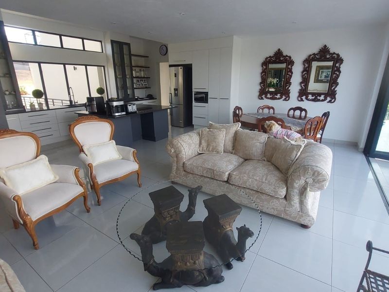 Spacious open-plan living and dining area featuring a modern kitchen with island, tiled floors, and large sliding doors leading to an outdoor space.