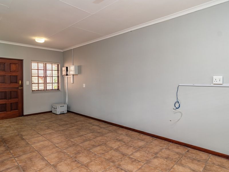 An empty living room featuring tiled flooring, a timber entrance door, and neutral wall finishes, ready for personalization.