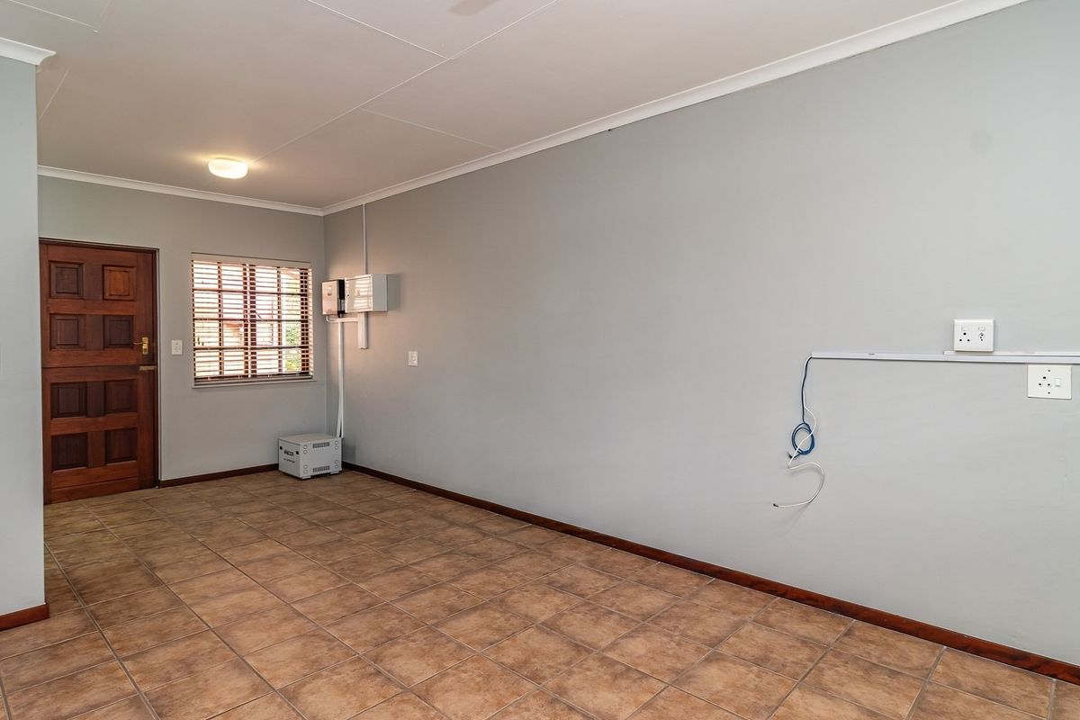 An empty living room featuring tiled flooring, a timber entrance door, and neutral wall finishes, ready for personalization.