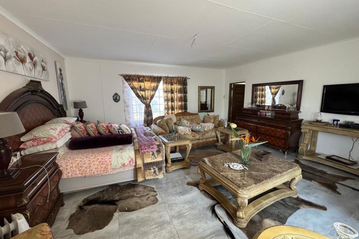 Spacious bedroom featuring large format floor tiles and neutral wall finishes, currently utilized as a multi-functional living and sleeping area.