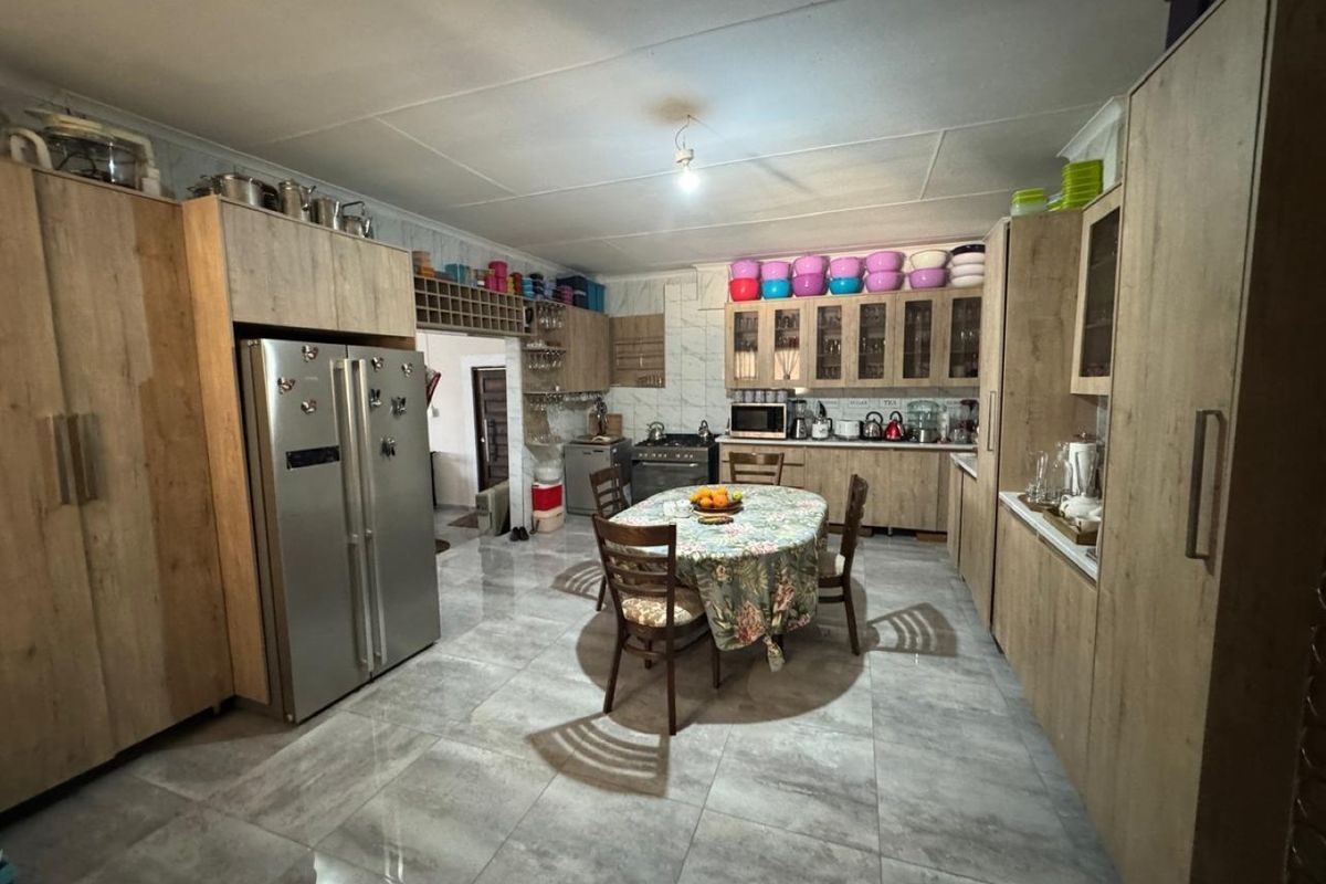 Spacious kitchen featuring modern wood-look cabinetry, tiled flooring, built-in oven and stove, and ample storage with integrated wine rack.