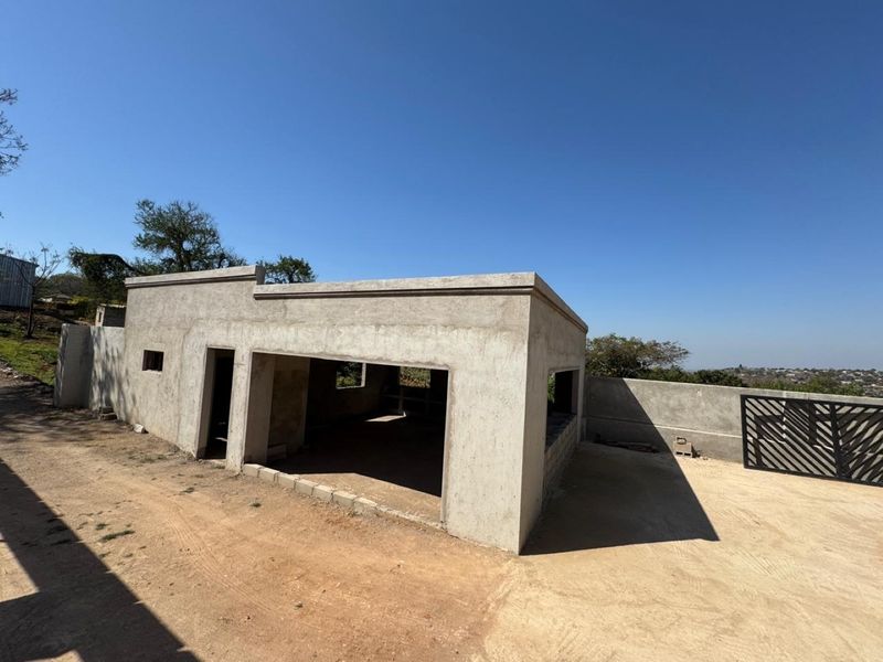 An unfinished concrete structure on a farm property, featuring open-plan design potential and a metal entrance gate.