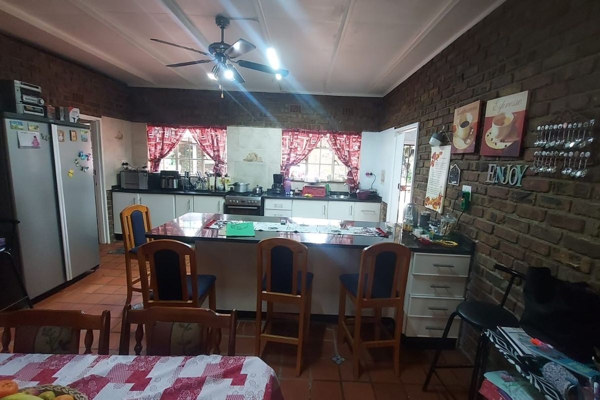 Spacious kitchen featuring exposed brick walls, a central island with seating, and functional cabinetry, offering a rustic and practical cooking and dining space.