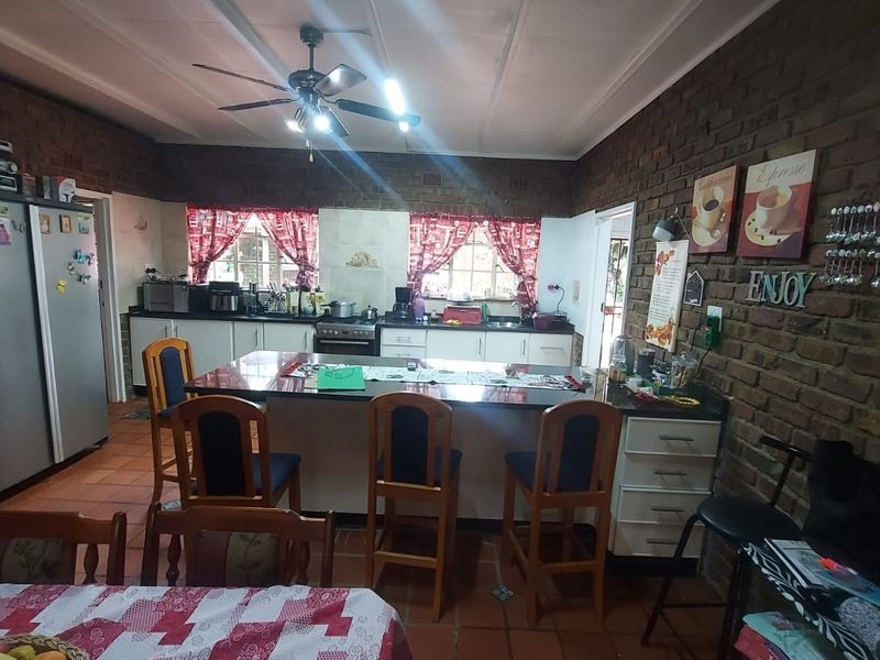 Spacious kitchen featuring exposed brick walls, a central island with seating, and functional cabinetry, offering a rustic and practical cooking and dining space.