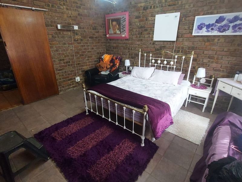 A bedroom featuring rustic exposed brick walls and tiled flooring, providing a warm and textured aesthetic.