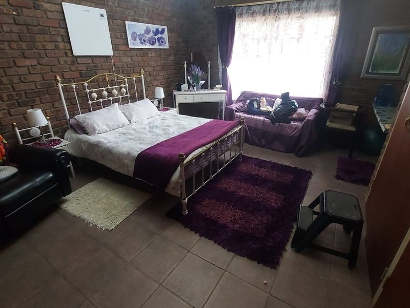 A bedroom featuring exposed brick walls, tiled flooring, and a built-in cupboard, offering a rustic aesthetic with potential for modernization.