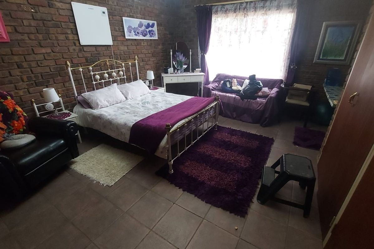 A bedroom featuring exposed brick walls, tiled flooring, and a built-in cupboard, offering a rustic aesthetic with potential for modernization.