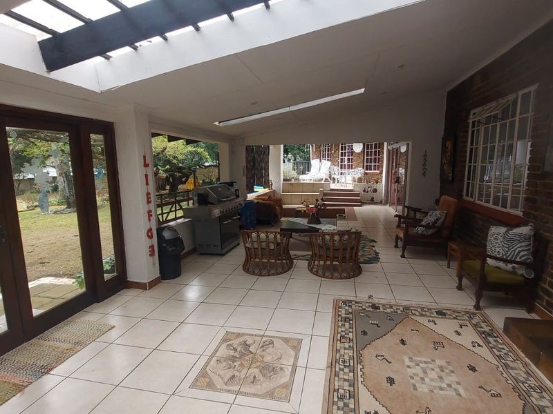 Spacious covered patio featuring tiled flooring, a large skylight, and an exposed brick wall, providing a versatile outdoor entertainment area.