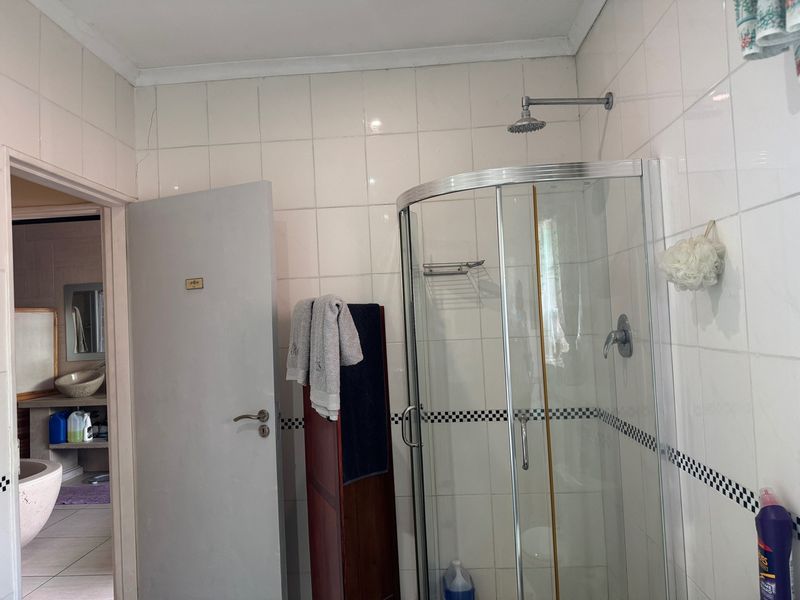 A functional bathroom featuring a corner shower enclosure with tiled walls and visible signs of wear.