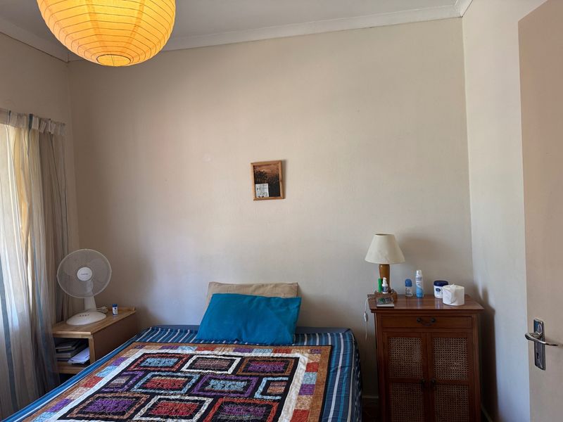 A standard bedroom featuring neutral walls, a window with curtains, and coving detail.