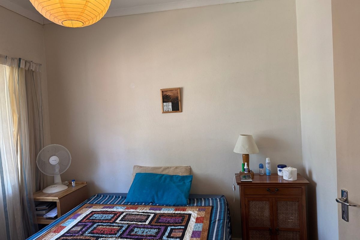 A standard bedroom featuring neutral walls, a window with curtains, and coving detail.