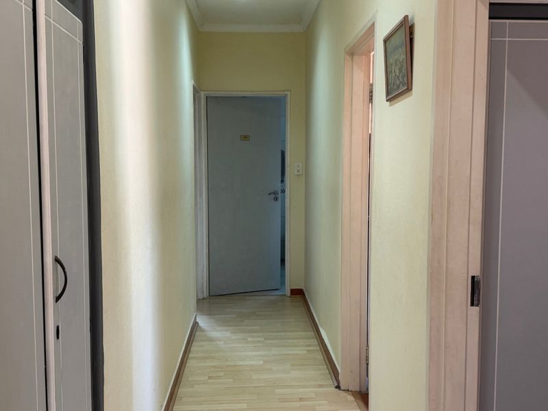 A functional hallway featuring laminate flooring and built-in storage cupboards, providing access to multiple rooms within the home.