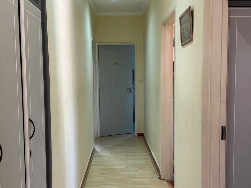 A functional hallway featuring laminate flooring and built-in storage cupboards, providing access to adjacent rooms within the home.