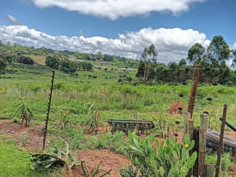 A scenic view of the farm landscape featuring open fields, rolling hills, and perimeter electric fencing with wooden posts.