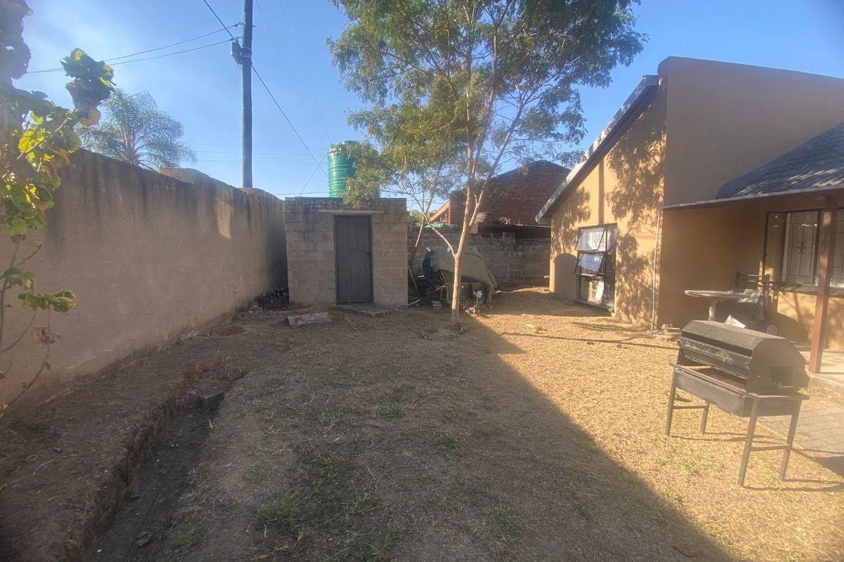Rear garden area featuring a perimeter boundary wall, a small outbuilding with a water tank, and direct access to the main house structure.