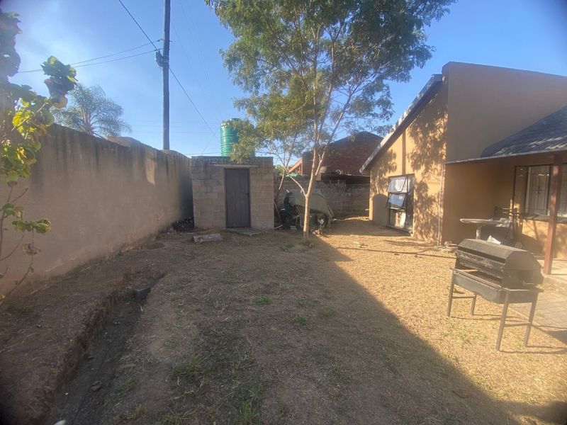 Rear garden area featuring a perimeter boundary wall, a small outbuilding with a water tank, and direct access to the main house structure.