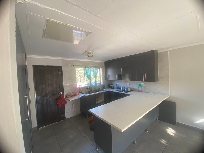 A functional kitchen featuring dark cabinetry, a breakfast counter, tiled flooring, and a built-in hob with an extractor fan.