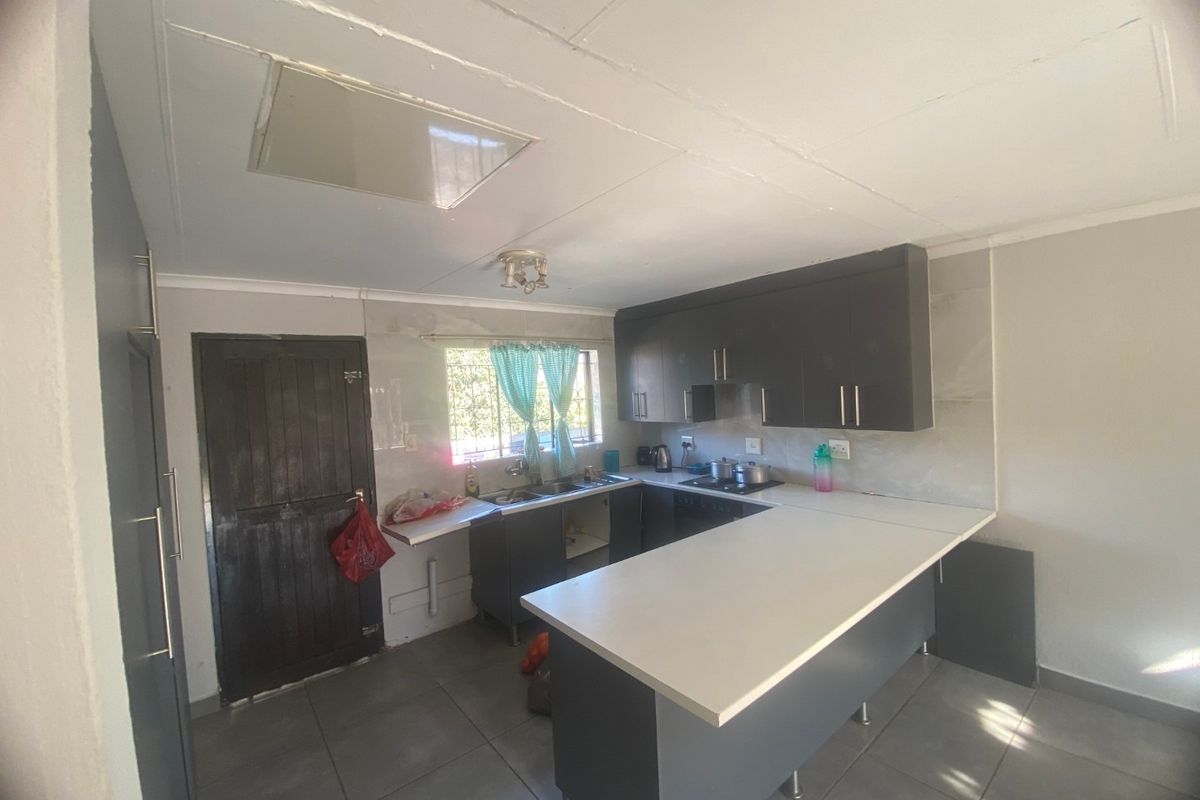 A functional kitchen featuring dark cabinetry, a breakfast counter, tiled flooring, and a built-in hob with an extractor fan.