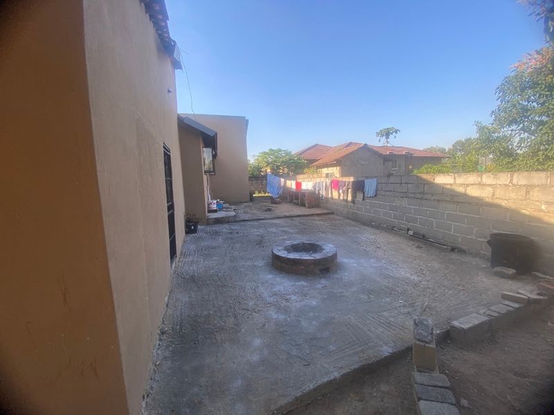 Rear exterior area featuring a concrete patio, a built-in fire pit, and a perimeter brick boundary wall.