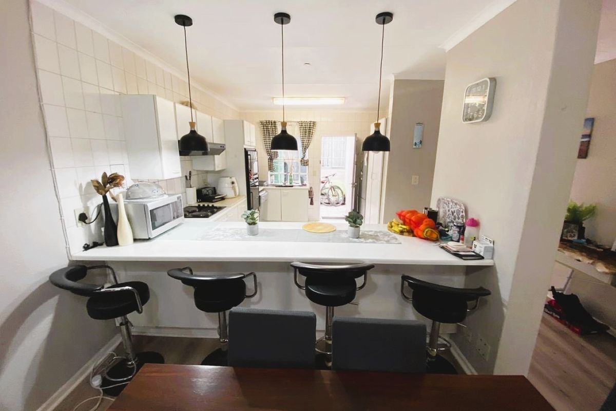 A functional kitchen featuring a breakfast bar, built-in cabinetry, and a tiled backsplash, providing a practical layout for daily meal preparation.