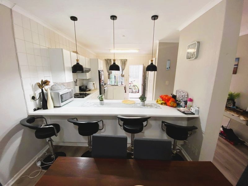 A functional kitchen featuring a breakfast bar, built-in cabinetry, and a tiled backsplash, providing a practical layout for daily meal preparation.