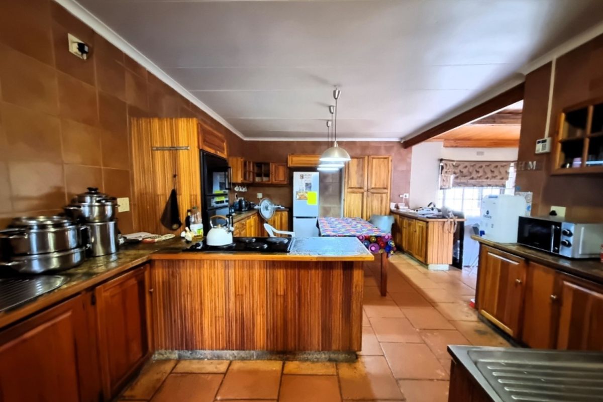 Spacious kitchen featuring extensive wooden cabinetry, tiled flooring, and a functional layout with integrated cooking appliances and ample counter space.