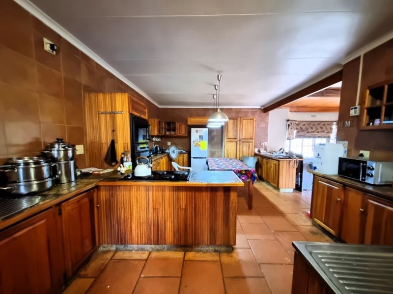Spacious kitchen featuring extensive wooden cabinetry, tiled flooring, and a functional layout with integrated cooking appliances and ample counter space.
