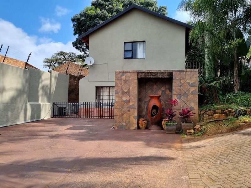 Front exterior view of the property featuring a paved driveway, secure gated access, and a decorative tiled feature wall.
