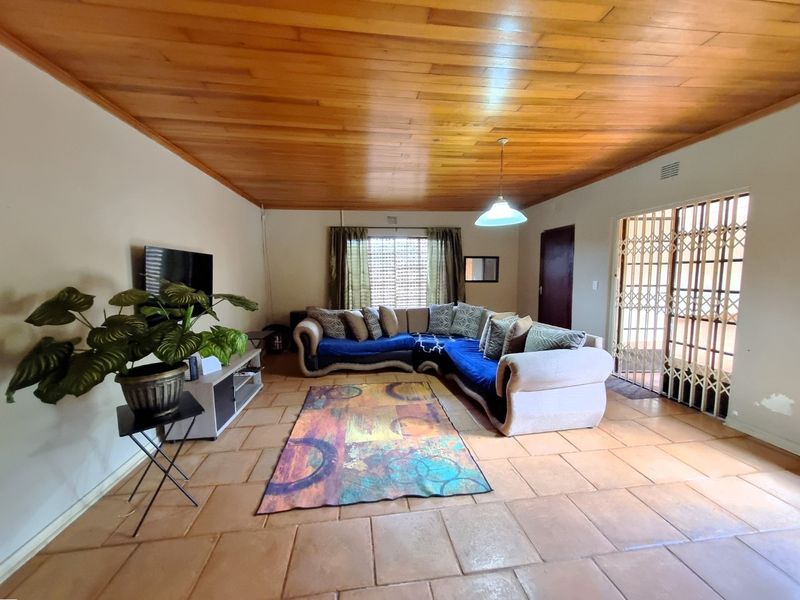 Spacious living room featuring a warm timber ceiling, ceramic tiled flooring, and a security gate leading to the exterior.